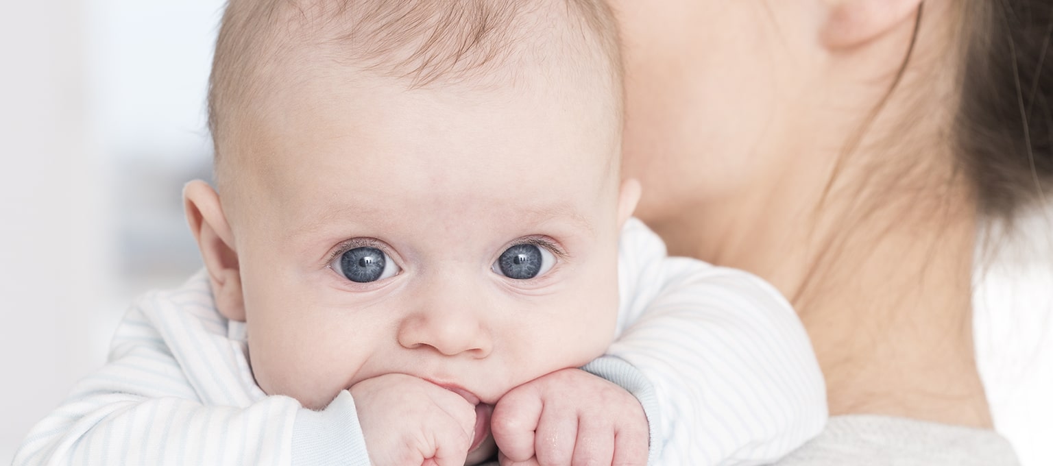 Mother holding her blue-eyed baby on her shoulder