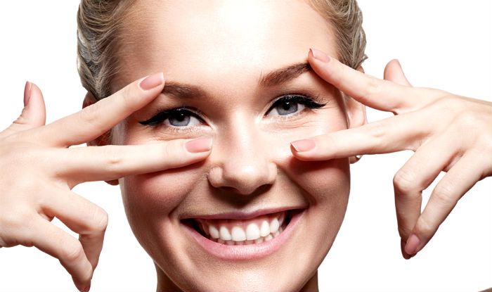 woman with blonde hair holding her fingers up to her eyes and smiling