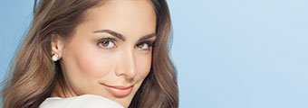 young brunette woman smiling towards the camera against a blue background