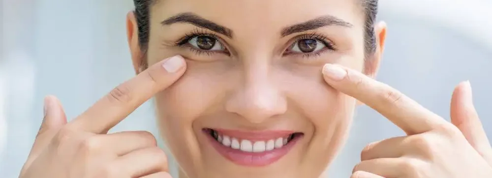 Woman smiling and pointing at her brown eyes