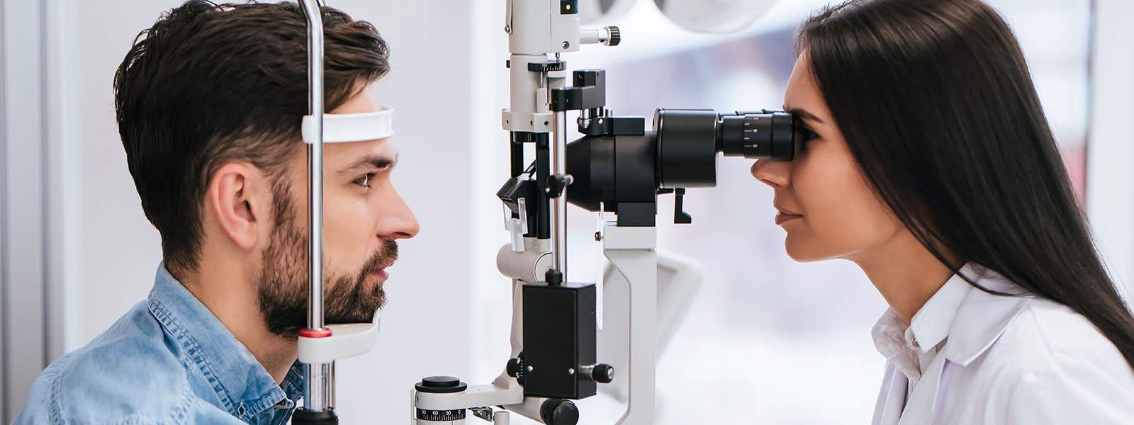 An eye doctor examining a young man through the machine